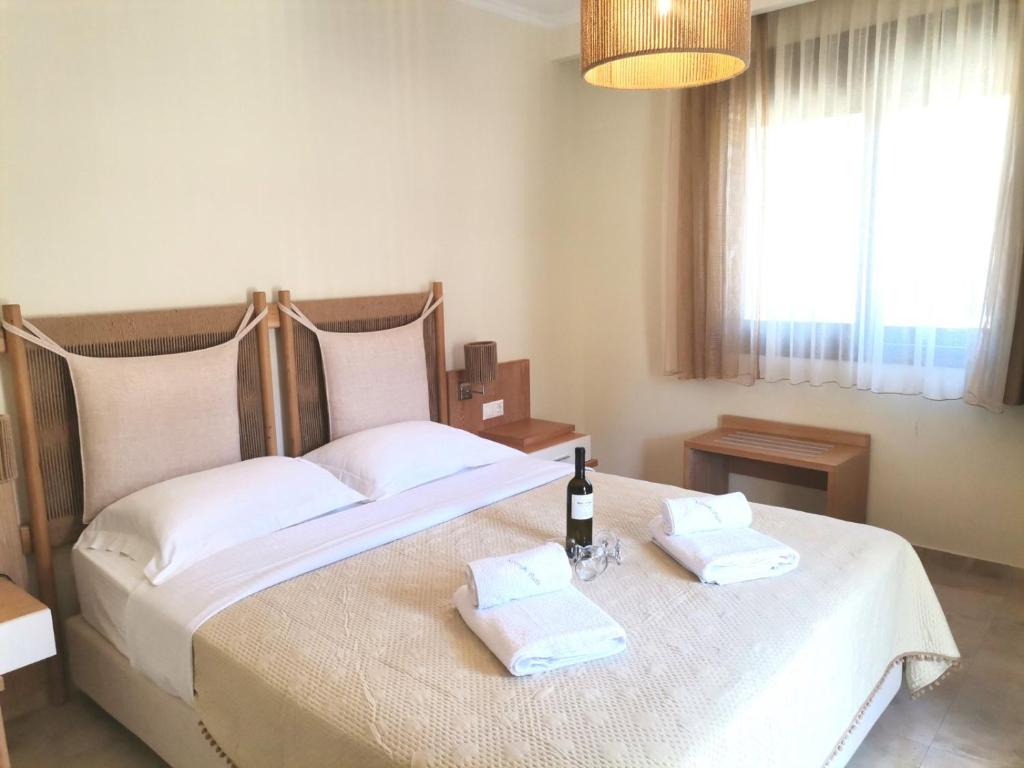 Mūsdienīga guļamistaba ar divguļamo gultu, dabīga koka mēbelēm un gaišu interjeru, kurā redzama pudele vīna un dvieļi uz gultas.