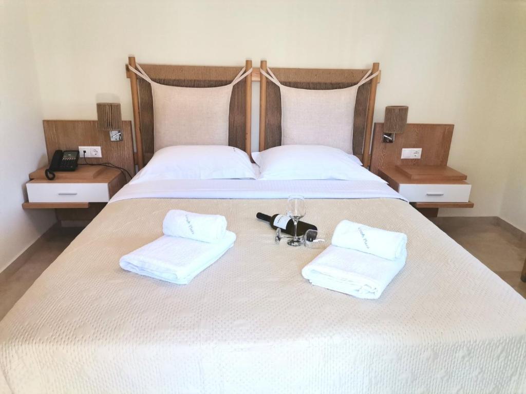 Mūsdienīga guļamistaba ar ērtu divguļamo gultu, dekoratīvām spilveniem un vīna pudeli ar glāzēm uz gultas. Sienas ir gaišas, bet mēbeles ir koka ar minimālistisku dizainu.