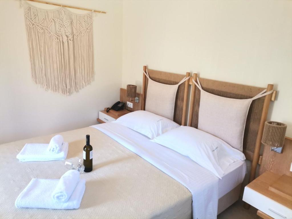 Mūsdienīga guļamistaba ar divguļamo gultu, dekori no dabīgiem materiāliem un šampanieša pudeli uz naktsgaldiņa. Sienā ir izšūta makramē dekorācija, radot mājīgu atmosfēru.