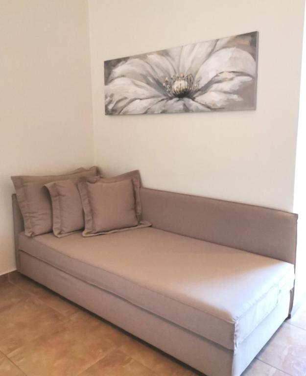 Mūsdienīgs dīvāns ar neitrālu krāsu un spilveniem, kas papildina telpas estētiku, kas rotāts ar ziedu gleznu virs tā.