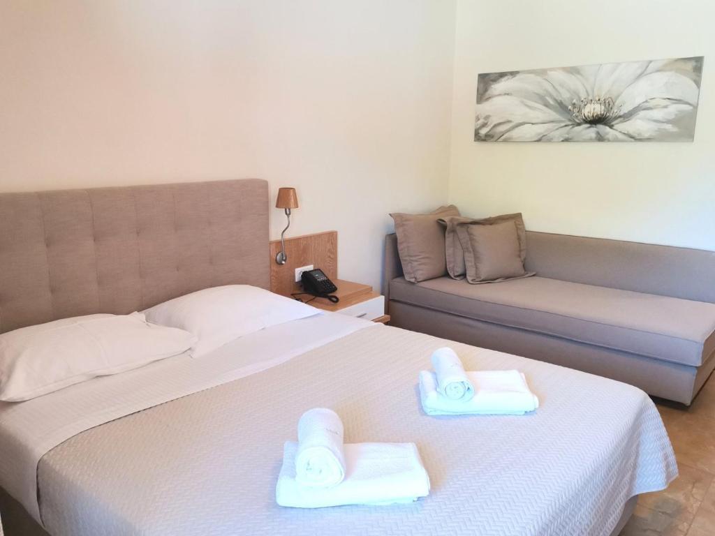 Mūsdienīga viesnīcas numura iekārtojums ar divguļamo gultu, atpūtas dīvānu un dekoratīvu mākslas darbu uz sienas. Gultā ir salocītas dvieļi, kas piešķir viesnīcas atmosfēru.