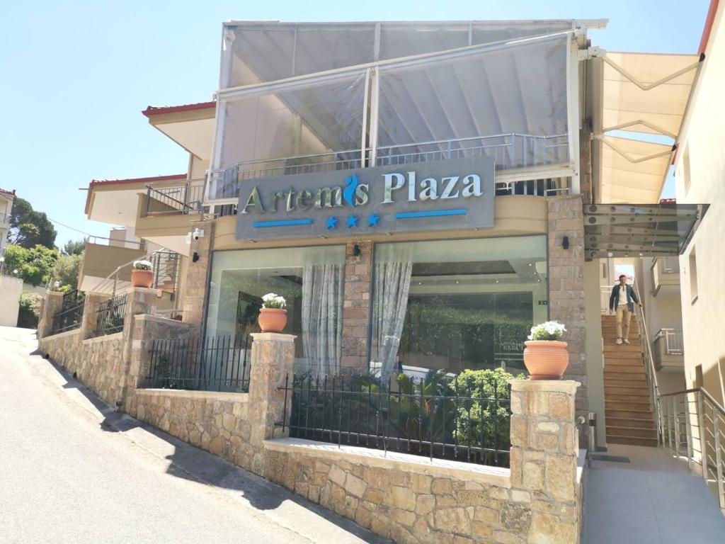 Artem's Plaza viesnīca ar modernu arhitektūru un akmens sienām, kas atrodas kalnainā apvidū. Viesnīcas ieeja ir stilīga un viesmīlīga, ar augu dekorācijām.