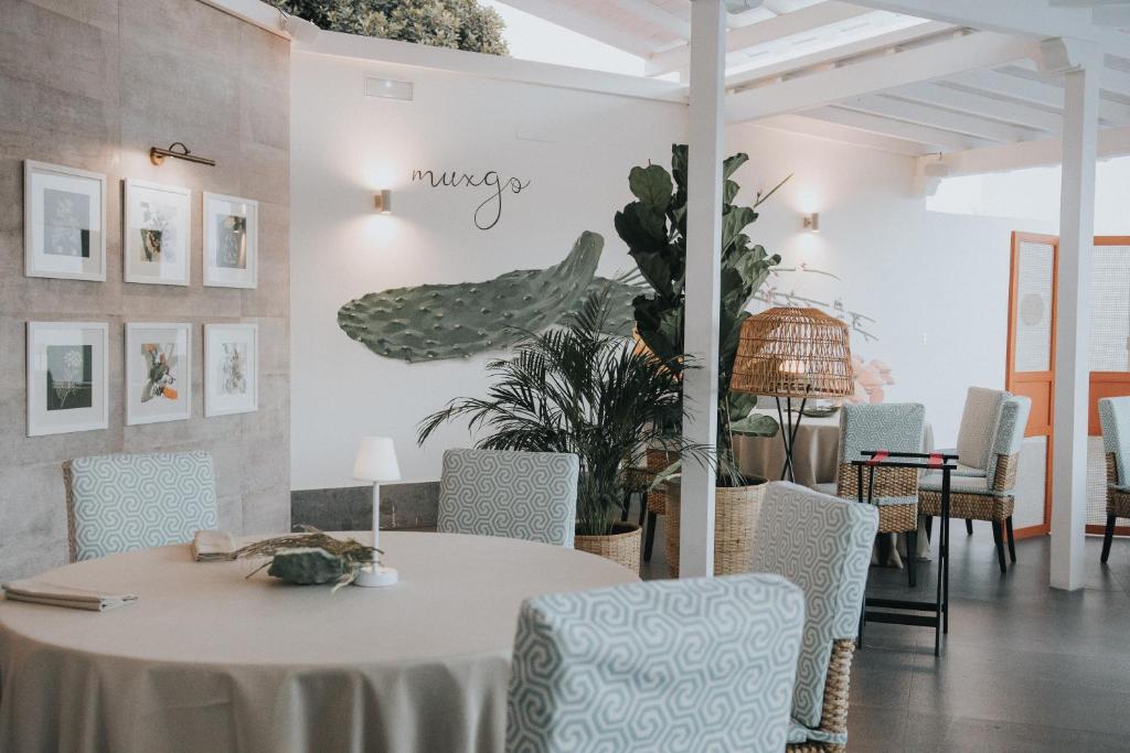 Mūsdienīgs restorāna interjers ar dabīgiem elementiem, kas ietver augu dekorācijas un mākslas darbus uz sienām. Sēdvietas ar elegantiem galdautiem un komfortablām krēslām rada patīkamu atmosfēru.