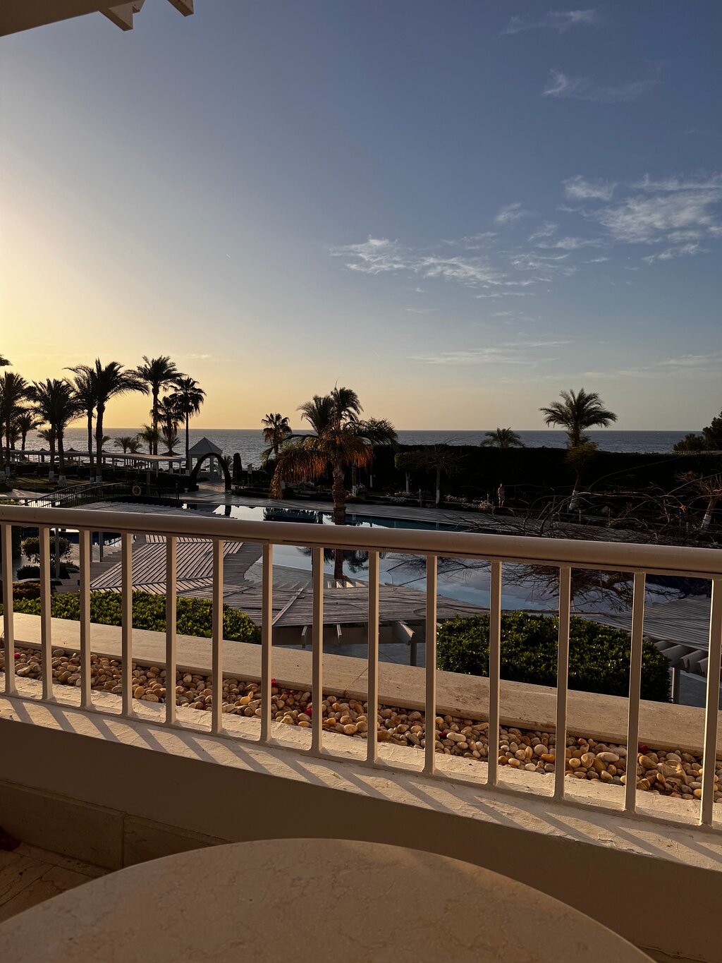 Skats no balkona uz jūru, palmas un baseinu, kur saule noriet. Daba un atpūtas vibes. panoramic view with beach and pools