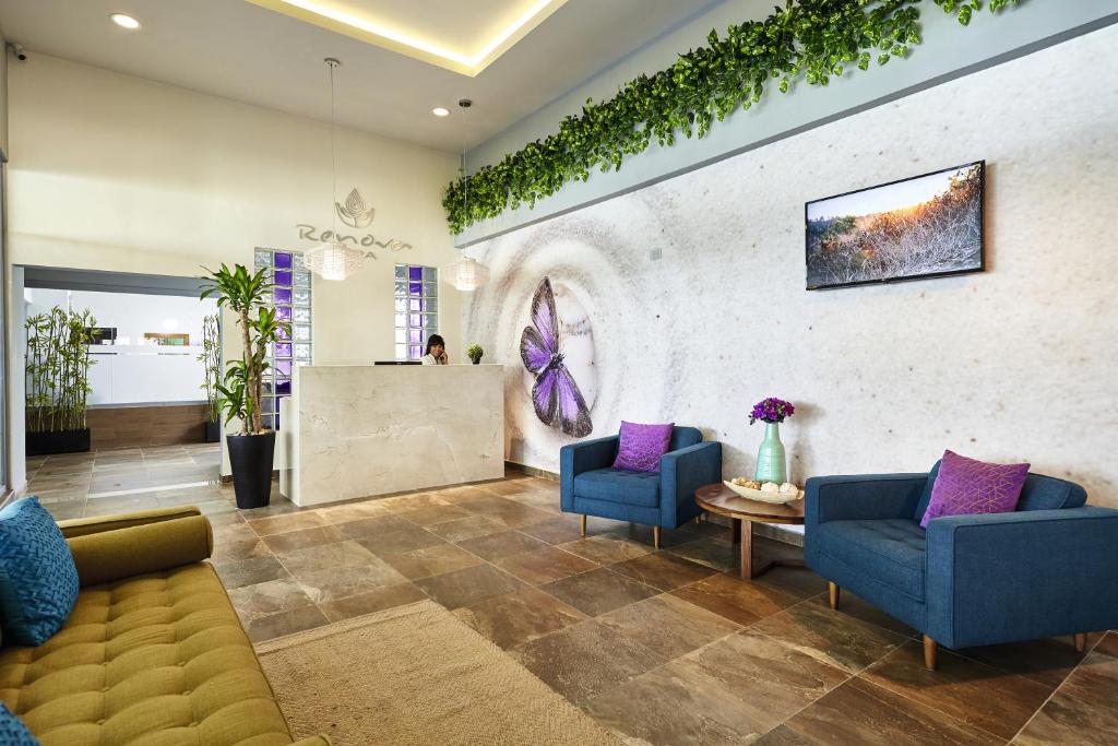 Mūsdienīga un eleganta uzgaidāmā telpa ar ziediem un dekoratīvām augu kompozīcijām, kas rada relaksējošu atmosfēru. Telpas centrā ir recepcija un komfortabli krēsli ar spilveniem.