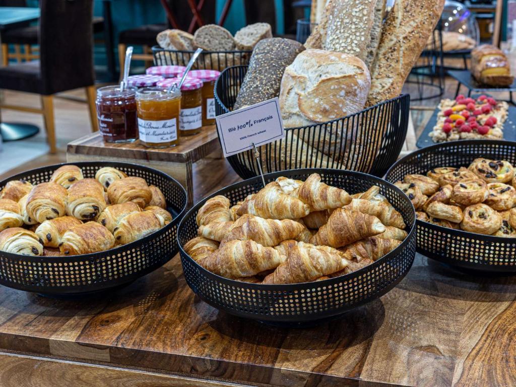 Svaigu maizīšu un konditorejas izstrādājumu bufete, kurā redzami dažādi croissant un maizes izstrādājumi, kā arī ievārījumi un augļi.