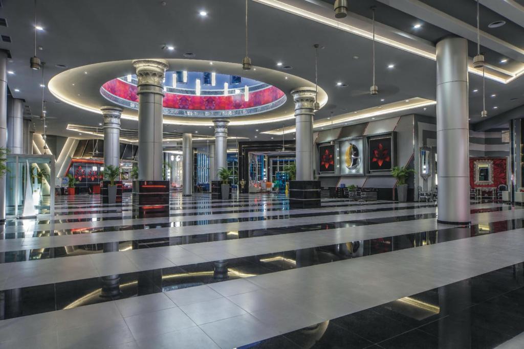 Mūsdienīgs viesnīcas vestibils ar elegantām kolonnām un mirdzošām gaismām, kas veido iespaidīgu atmosfēru. Grīda ar melnbaltām svītrām un dekoratīviem elementiem piešķir stilīgu izskatu.