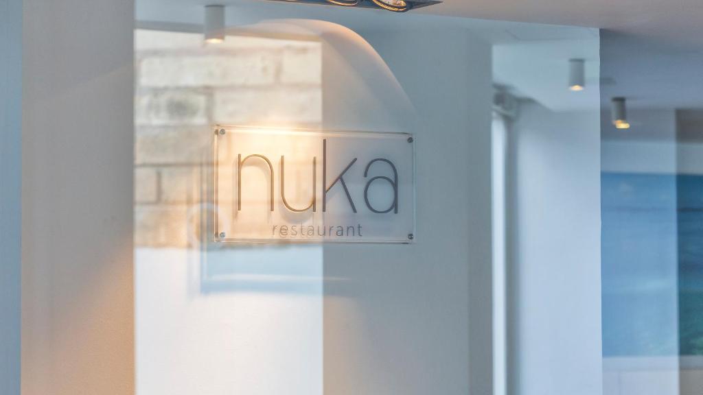 Nuka restorāna signāls ar modernu dizainu un gaišu fonu, kas rada patīkamu atmosfēru.