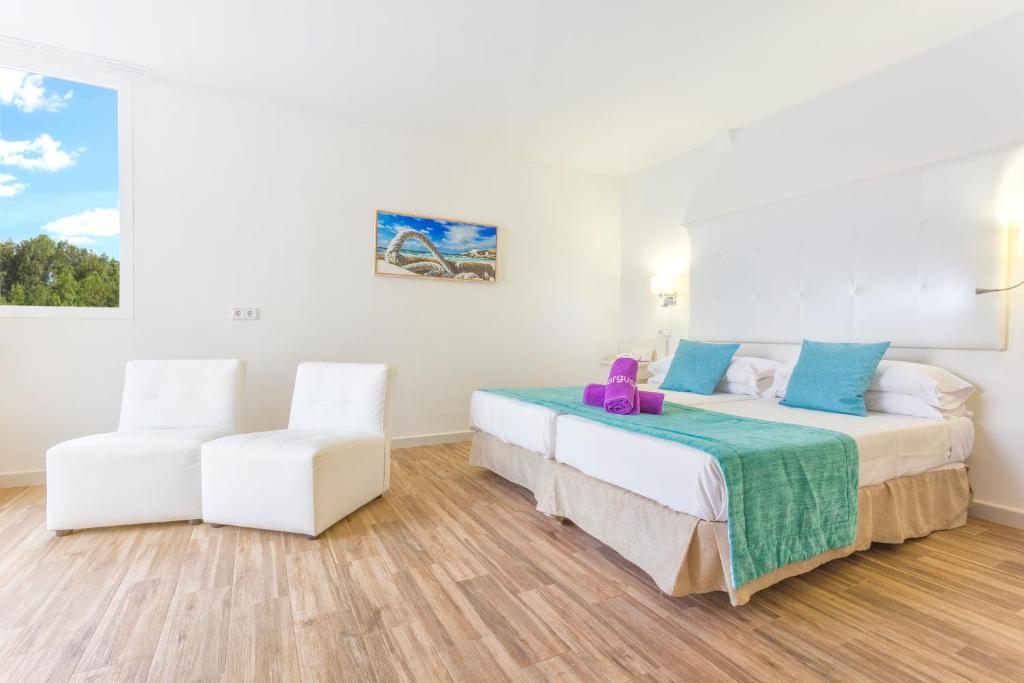 Mūsdienīgs viesnīcas numurs ar divām gultām, baltām krēslām un skatu uz dabu caur lielu logu. Interjers ir gaišs un ērts, ar aksesuāriem zilos toņos.