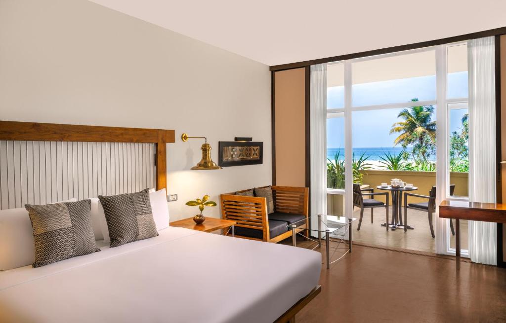 Moderns viesnīcas numurs ar skatu uz jūru, iekārtots ar ērtu gultu, stūri ar atpūtas mēbelēm un balkonu. Gaismas pieplūdums no lielajiem logiem rada patīkamu atmosfēru.