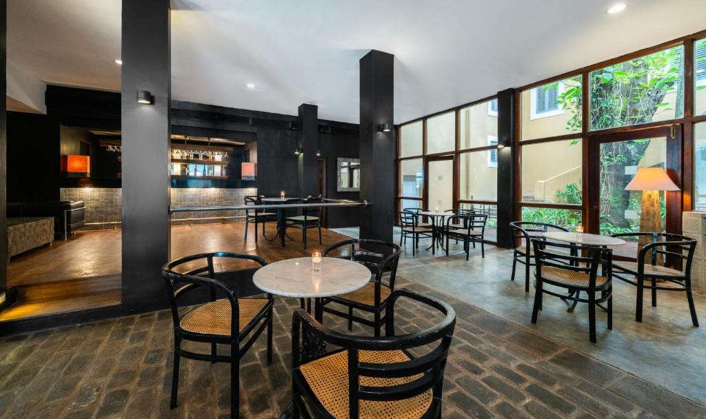 Moderns kafejnīcas interjers ar melnām sienām, marmora galdiem un koka krēsliem, kas piedāvā patīkamu atmosfēru. Lieli logi nodrošina dabīgu apgaismojumu un skatu uz zaļo dārzu.