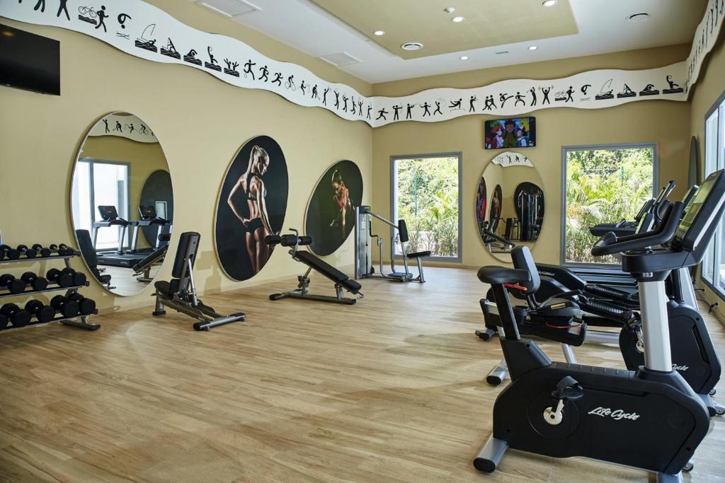 Moderns sporta zāles interjers ar trenažieriem, svariem un lieliem spoguļiem, kas atspoguļo aktīvu dzīvesveidu. Telpā ir arī ekrāns, kas var rādīt nodarbības vai sporta pasākumus.