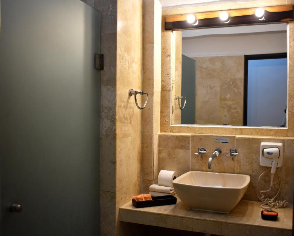 Mūsdienīgs vannas istabas interjers ar stikla dušas durvīm, elegantu izlietni un gaismas spuldzēm virs spoguļa.