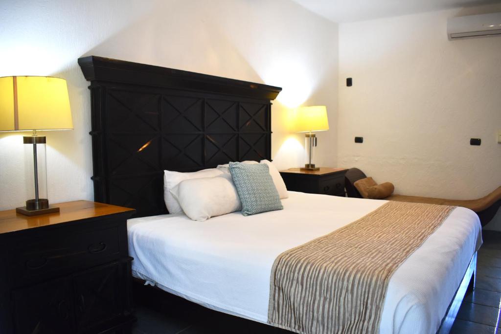 Mūsdienīgas guļamistabas interjers ar lielu gultu, melnu galvas dēli un naktsgaldiņiem. Telpā ir silta apgaismojuma lampas un ērts dīvāns.