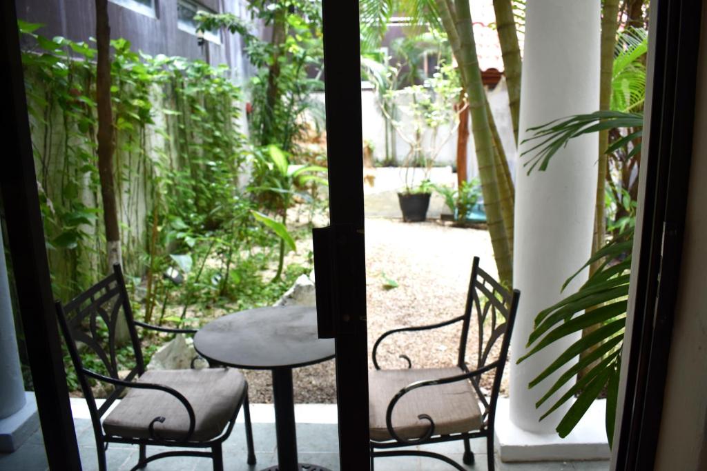 Miers un relaksācija viesnīcas terasē ar divām krēsliem un galdu, skats uz zaļo dārzu.