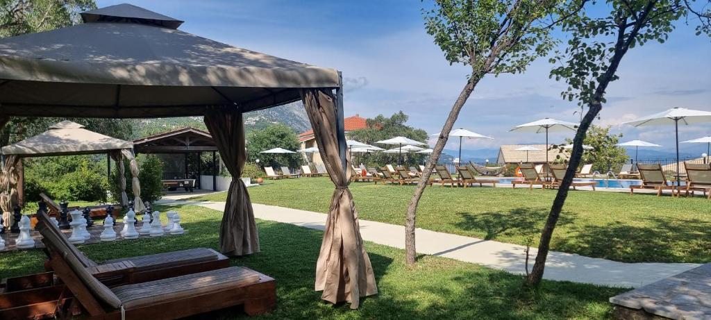 Labi iekārtota atpūtas zona ar saulessargiem un sauļošanās krēsliem pie peldbaseina, blakus ir šaha galds un zaļa zāle. Ideāla vieta relaksācijai un izklaidei.