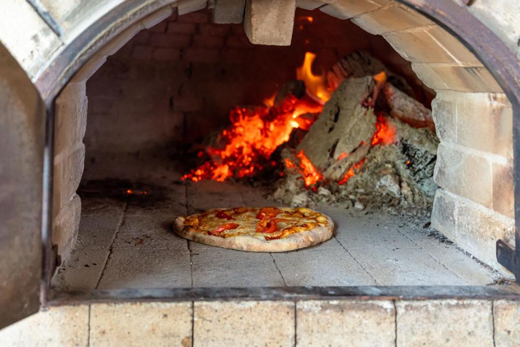 Koka krāsnī cepta pica ar sarkanām paprikām un izteiksmīgu liesmu fonā. Izteiksmīga picu cepšanas atmosfēra.