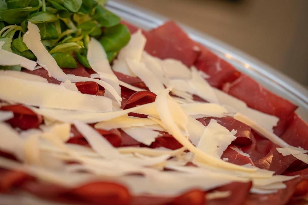 Svaigi sagatavots šķīvis ar plānām šķēlītēm no gaļas un rīvētu sieru, papildināts ar zaļajiem salātiem.