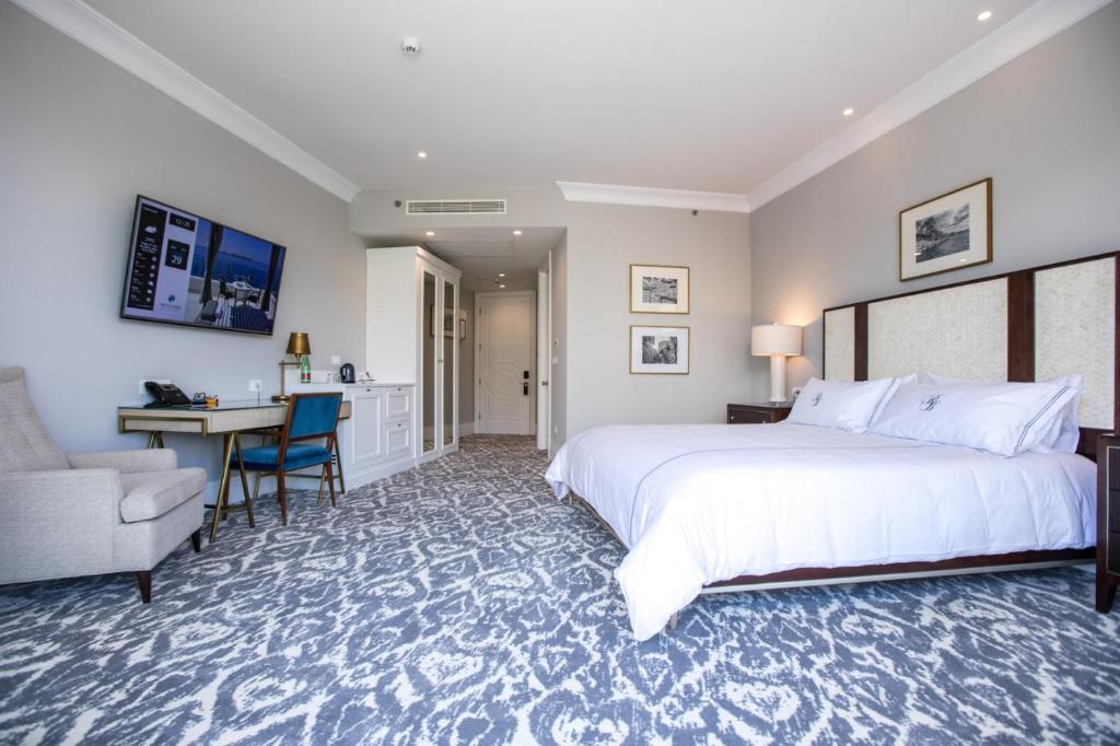 Mūsdienīga viesnīcas numura iekārtojums ar lielu gultu, darba galdu un televizoru. Telpa ir gaisa kondicionēta un ar elegantu paklāju, radot komfortablu atmosfēru.