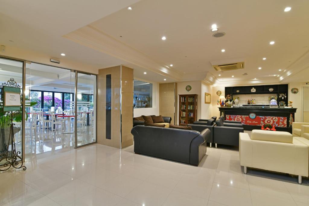 Eleganta viesnīcas uzgaidāmā zona ar mūsdienīgu interjeru, kurā ir ērti dīvāni un bārs. Logi piedāvā skatu uz āra terasi ar ziedošiem krūmiem.