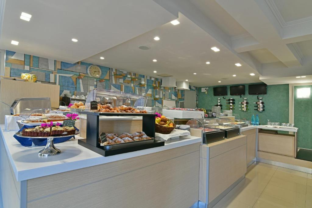 Mūsdienīgs kafejnīcas interjers ar plašu konditorejas izstrādājumu izvēli un svaigu augļu grozu, radot aicinošu atmosfēru.