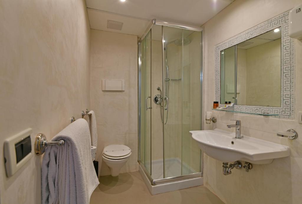 Mūsdienīgs vannas istabas interjers ar dušu, tualeti un izlietni, apgaismots ar siltu gaismu. Sienas ir neitrālās krāsās, radot svaigu un tīru atmosfēru.