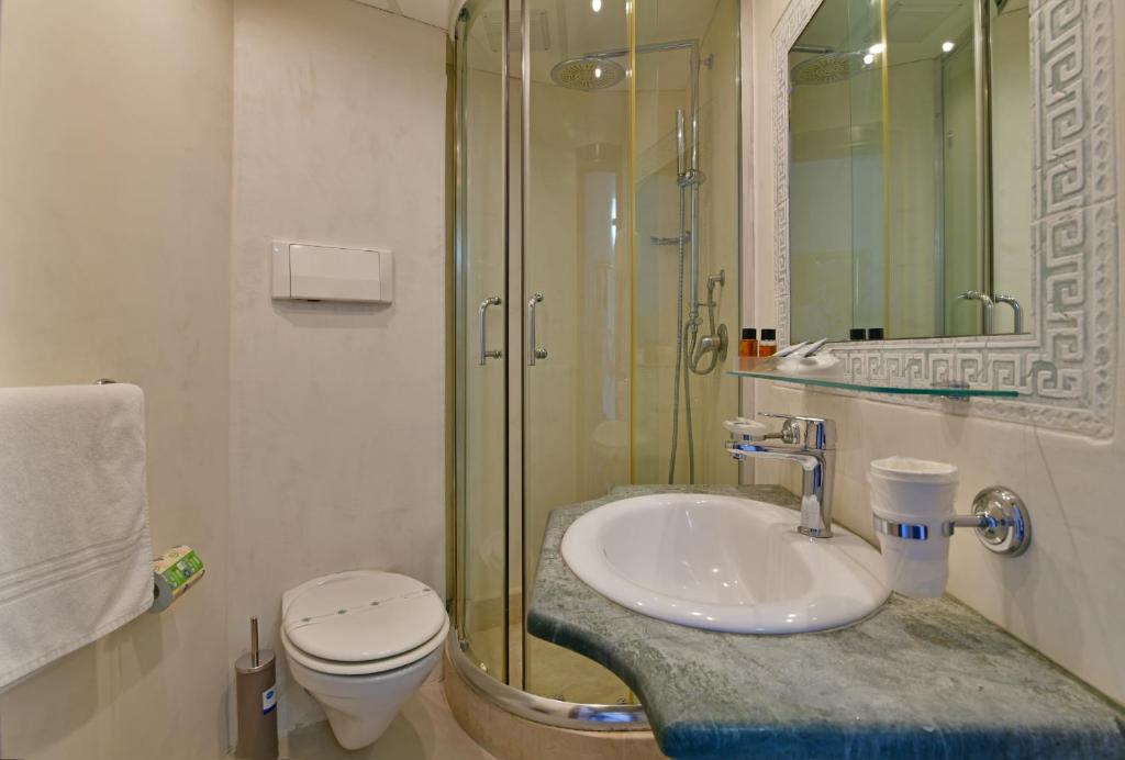 Mūsdienīgs vannas istabas interjers ar dušas kabīni, izlietni un tualeti, kas apvieno eleganci un funkcionalitāti. Vannas istaba ir gaiša un stilīga, ar akmens virsmu un spoguļiem.