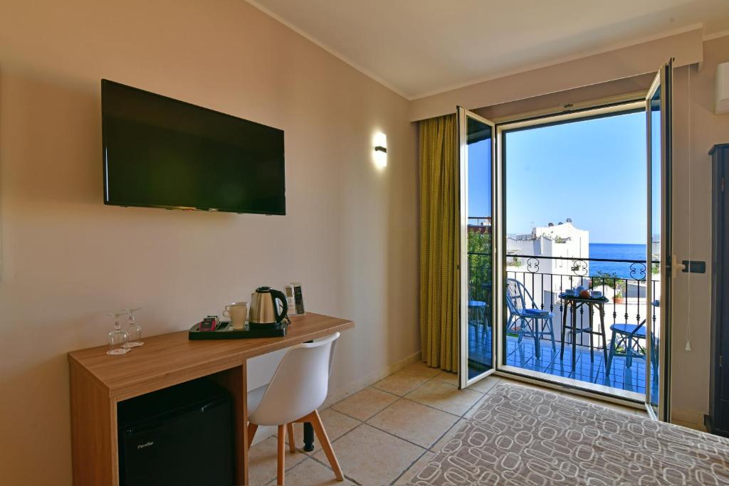 Mūsdienīga viesnīcas numura iekārtojums ar skatu uz jūru, kurā ir televizors, galds, krēslis un balkons. Numurā atrodas arī kafijas tējkanna un ledusskapis.