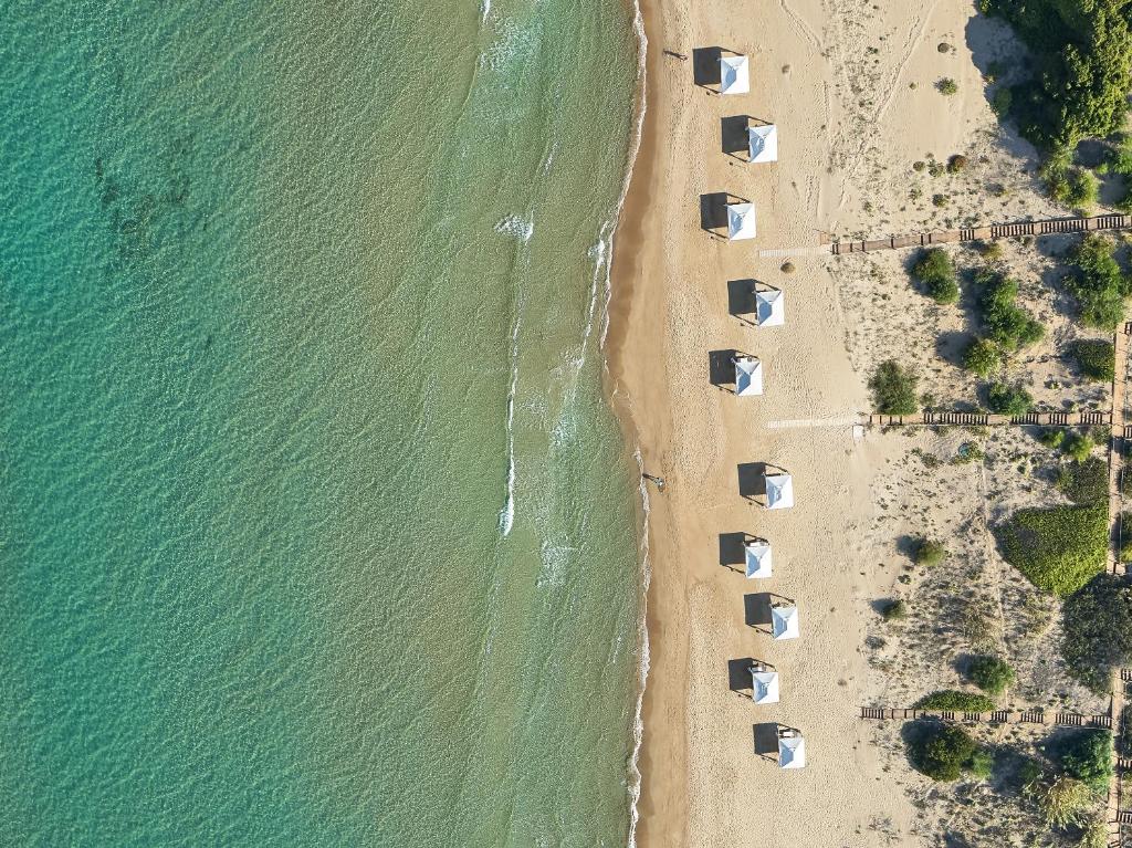 Pludmales ainava ar baltām nojām, kas izvietotas gar smilšu krastu, pie skaidri zila ūdens.