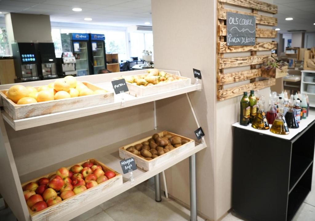 Augļu un dārzeņu stends ar dažādām sezonas precēm, kurā redzami āboli, bumbieri un kartupeļi, kā arī garšaugi un eļļas. Interjera elements ar dabīgu koka apdari.