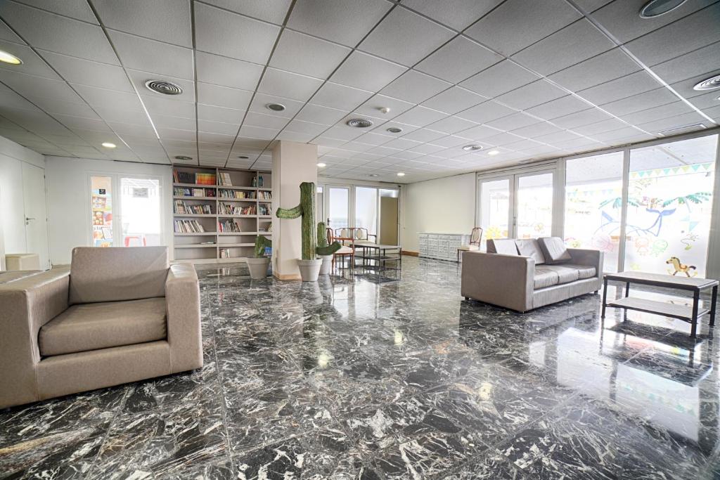 Mūsdienīgs interjers ar ērtām mēbelēm un grīdas segumu, kas rada plašu un gaišu atmosfēru. Telpā ir grāmatu plaukts un lieli logi, kas sniedz dabīgu apgaismojumu.