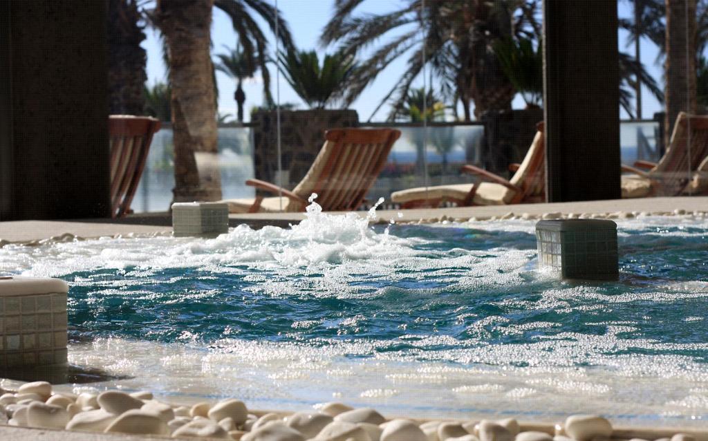 Relaksējoša spa vide ar burbuļojošu ūdeni un palmām fonā, kas rada mierīgu atmosfēru. Ideāli piemērota atpūtai un relaksācijai.