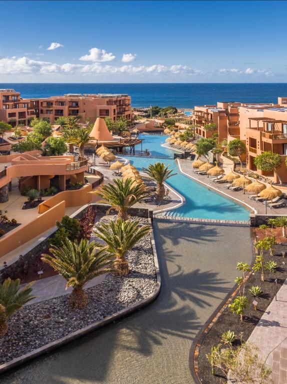 Tropu kūrorts ar baseinu, palmām un skatu uz jūru. Mierīga un saulaina atmosfēra, ideāla atpūtai un relaksācijai.