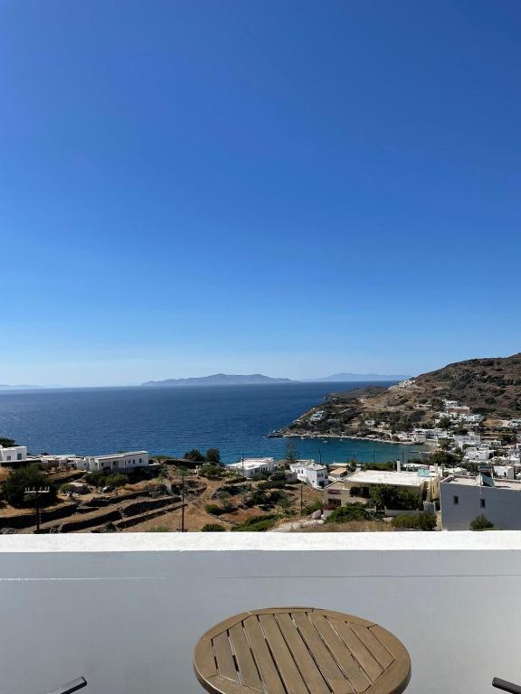 Skats uz jūru un kalnu ainavu ar baltiem māju jumtiem, kas veido gleznainu skatu. Skaidras debesīs un mierīgs ūdens papildina ainavu.