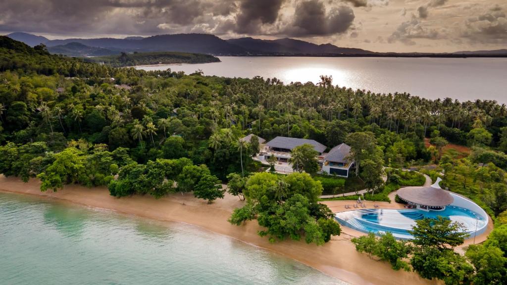 Skats uz Island Escape by Burasari piekrastes ainavu ar baseinu un zaļajiem kokiem.