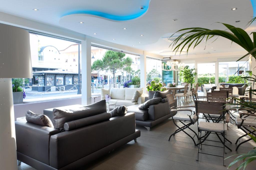 Mūsdienīgs un elegants interjers ar gaišām krāsām, dīvāniem un ēdamgaldiem, kas nodrošina patīkamu atmosfēru. Logi piedāvā skatu uz ārpusi, radot gaismas un telpas sajūtu.