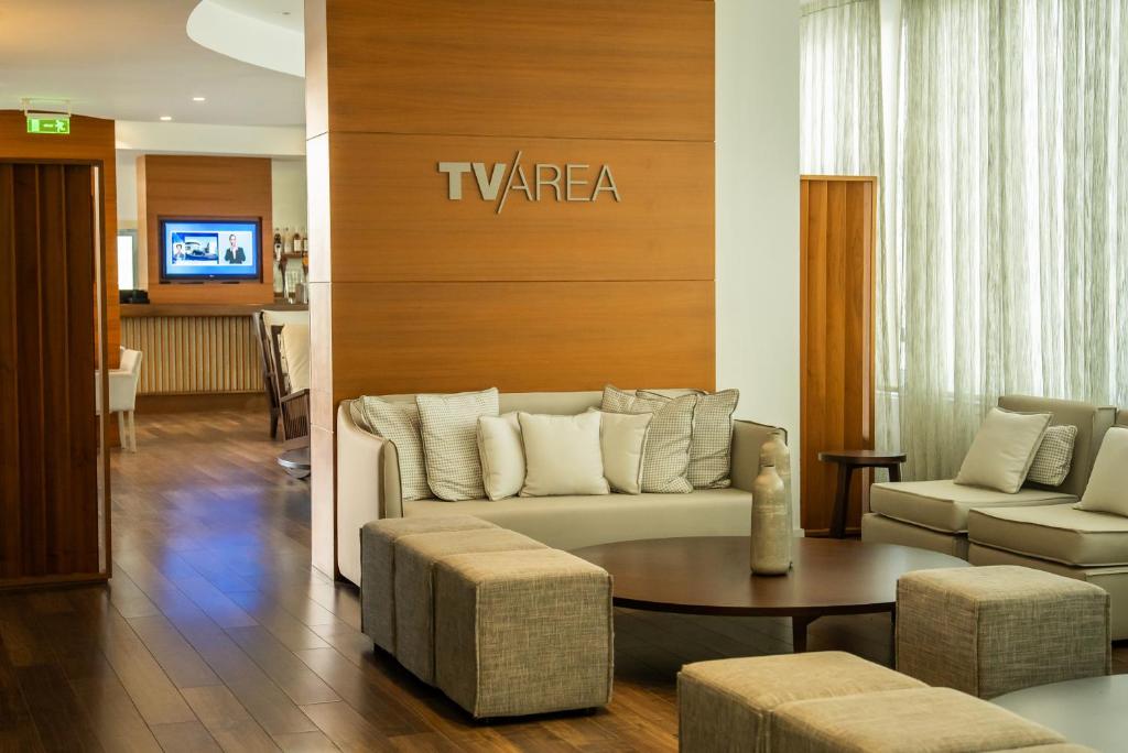 Mūsdienīgs atpūtas stūris ar ērtām mēbelēm, kurā ir redzama TV zona un eleganta koka apdare. Telpa ir gaiša un viesmīlīga, ar daudzām spilveniem un patīkamu atmosfēru.