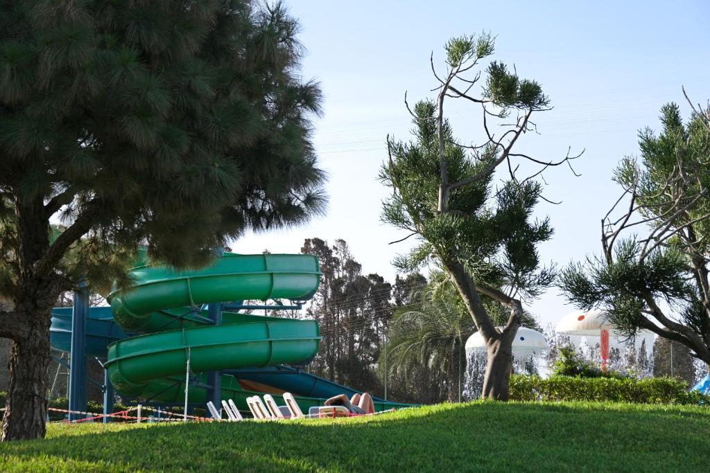 Zaļš ūdens slidkalniņš un koki atpūtas parkā, kas rada relaksējošu atmosfēru. Parkā redzamas arī citas izklaides iespējas, piemēram, ūdens atrakcijas.