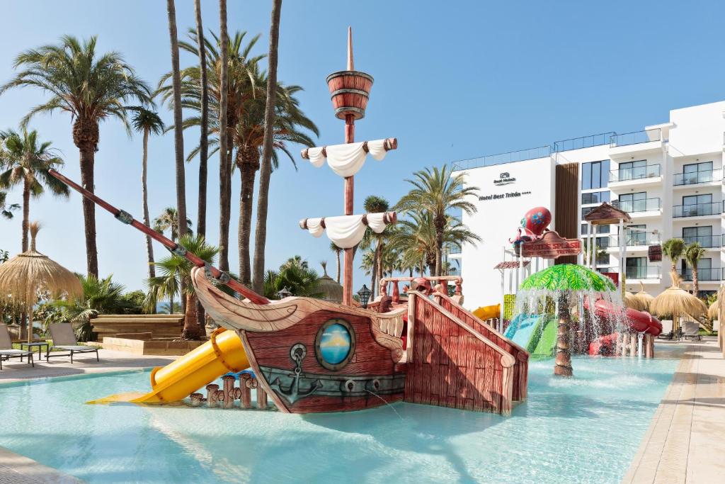 Piratku laiva ūdens slidkalniņš atrakciju parkā ar palmām un viesnīcu fona. Ideāla vieta ģimenēm un bērniem.