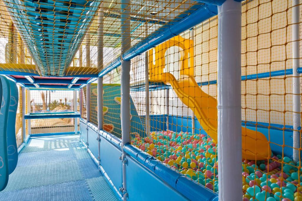 Bērnu spēļu laukums ar krāsainām bumbiņām, slidkalniņu un drošu tīklu. Ideāla vieta bērnu izklaidei un aktivitātēm.