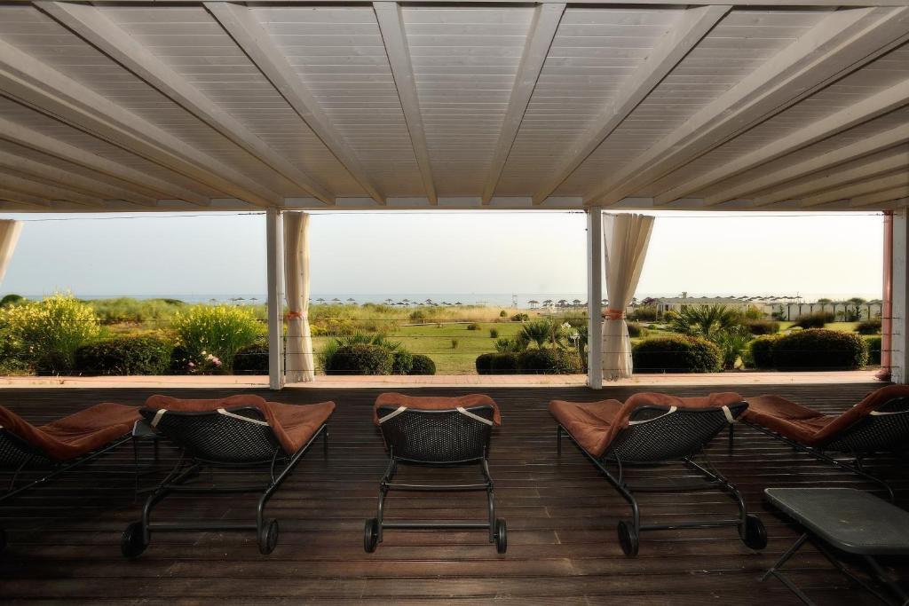 Skats no terases uz jūru, kur redzami atpūtas krēsli un apzaļumotas ainavas ar palmu kokiem. Ideāla vieta relaksācijai un atpūtai.