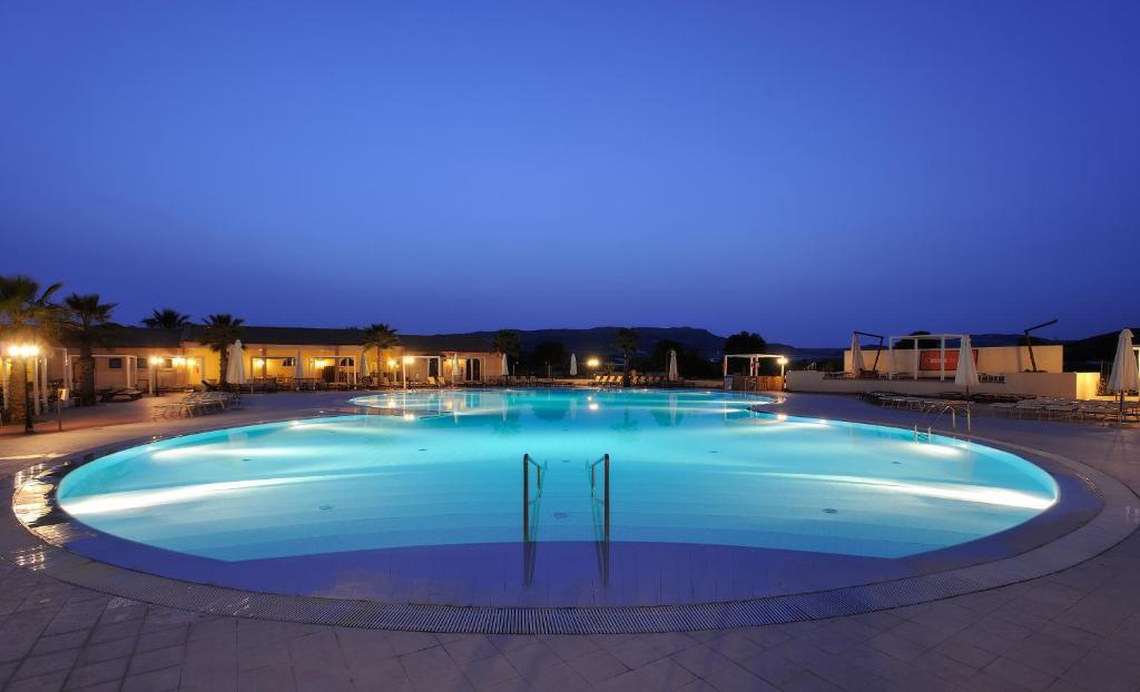 Lieliska nakts aina ar peldbaseinu, kas apgaismots ar zilu gaismu. Apkārt baseinam ir palmām un atpūtas krēsliem, radot relaksējošu atmosfēru.