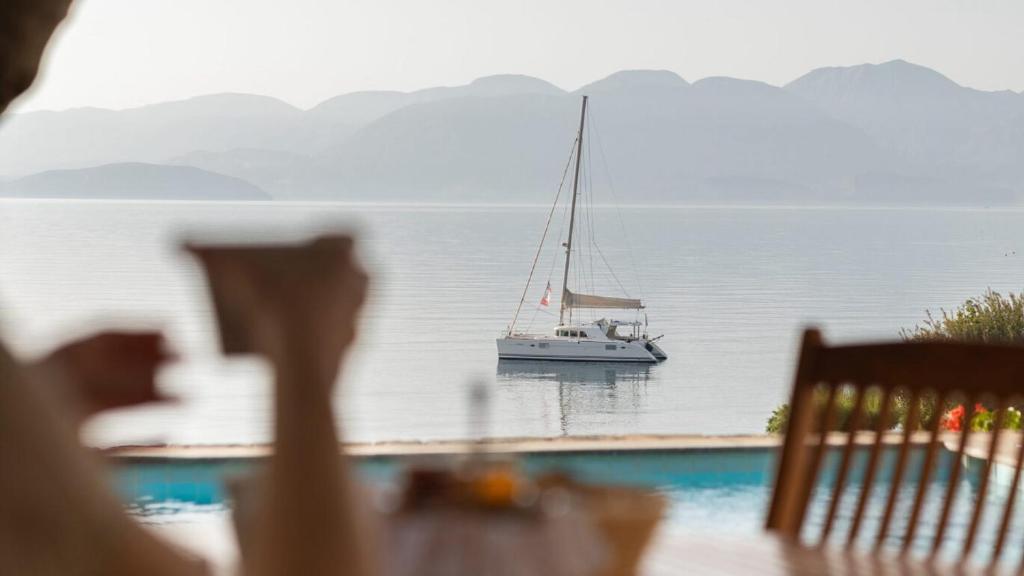 Relaksējošs skats uz laivu, kas peld pa mierīgu ūdeni, ar kalnu ainavu fona. Ideāla ainava, kas iedvesmo atpūtu un brīvību.