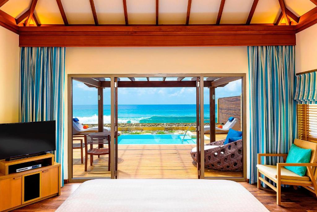 Elegants numurs ar skatu uz jūru, kur redzama terase ar baseinu un moderns interjers. Šī vieta iedvesmo relaksācijai un atpūtai.