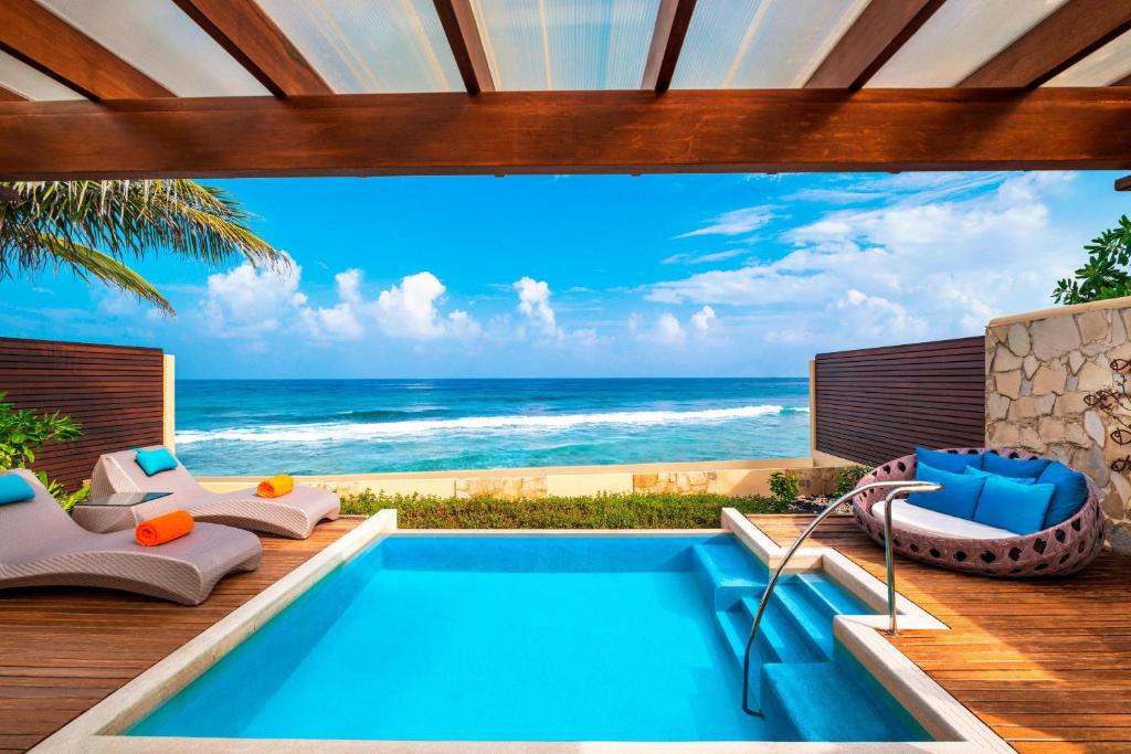 Greznas atpūtas zonas skats ar baseinu un saulessargiem, kas vērsti uz skaistu jūras ainavu. Skats uz zilo jūru un debesīm rada mierīgu un relaksējošu atmosfēru.