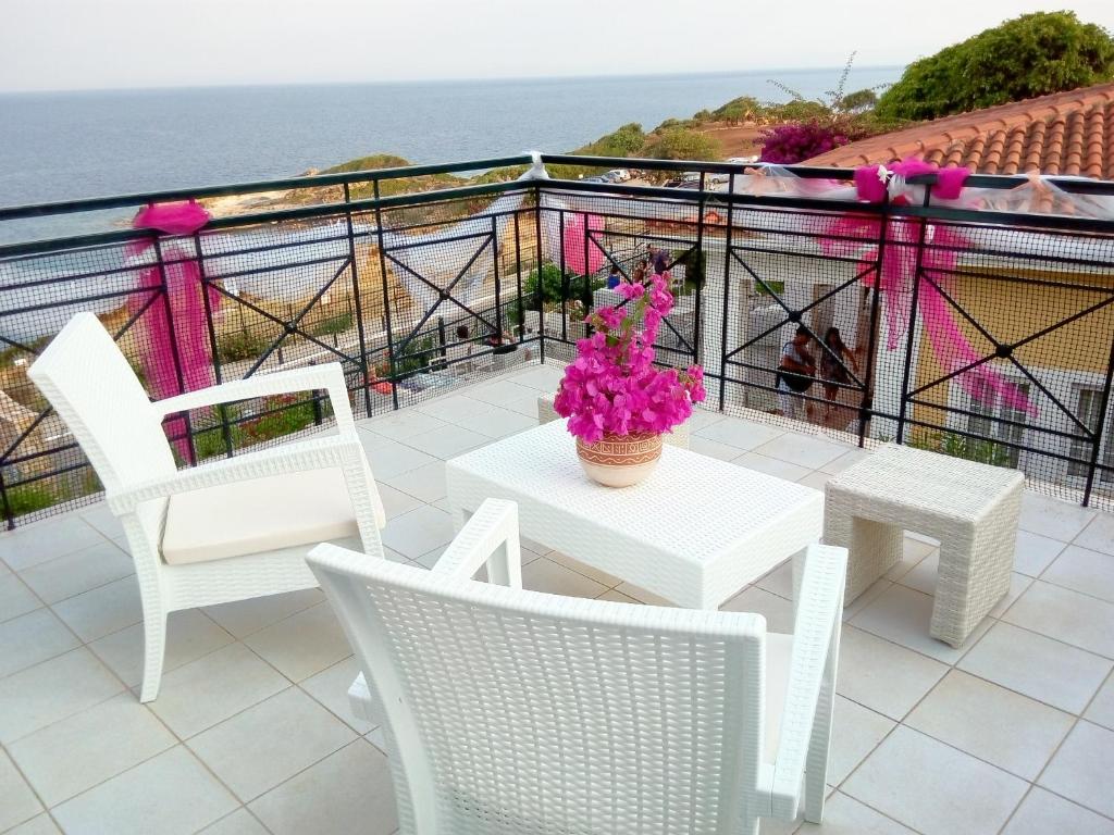 Balkons ar baltām mēbelēm un ziedu kompozīciju, skats uz jūru. Ideāla atpūtas vieta ar romantisku atmosfēru.