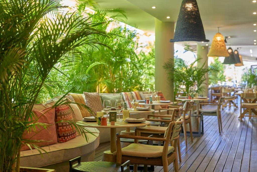 Mūsdienīgs restorāns ar zaļiem augiem un elegantiem galdiem, radot relaksētu atmosfēru. Interjerā ir koka grīda un izsmalcināta apgaismojuma dekorācija.