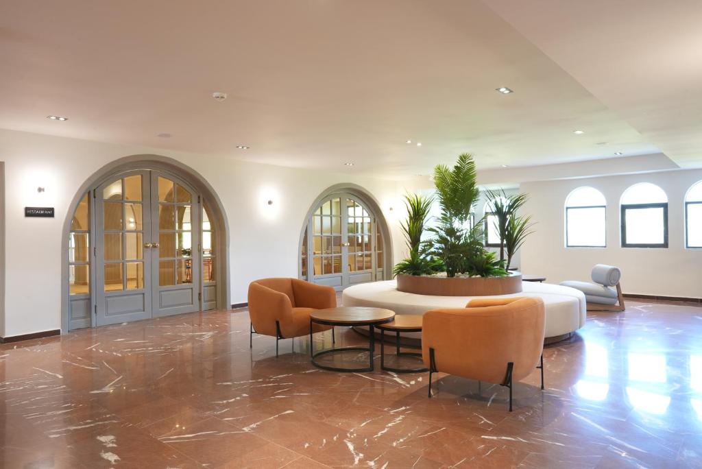 Mūsdienīgs interjers ar ērtām atpūtas zonām un zaļajiem augiem centrā, radot relaksējošu atmosfēru. Apgaismojums un elegantas durvis piešķir telpai mājīgu sajūtu.