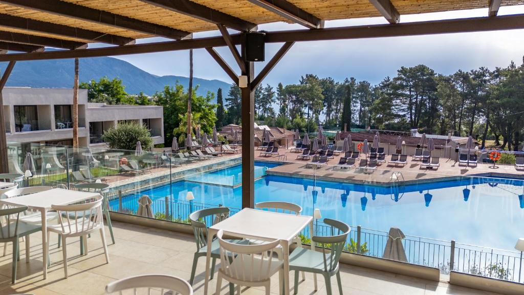 Mūsdienīgs viesnīcas restorāns ar skatu uz peldbaseinu un kalniem, ap kuru izvietotas sauļošanās krēsli un saulessargi. Ideāla vieta relaksācijai un izklaidei.