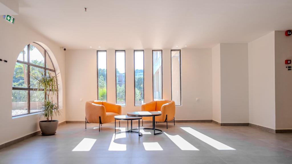 Mūsdienīga un gaisīga atpūtas zona ar oranžām krēslām un apaļu galdu, kas apgaismota ar dabīgu gaismu no lielajiem logiem. Ideāla vide relaksācijai un sarunām.